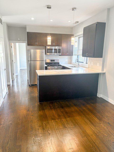 A kitchen with a black counter top and wooden floors.