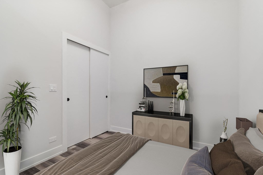 a bedroom with white walls and a white bed with a brown blanket