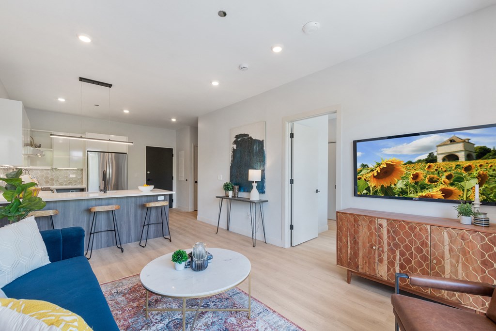 a living room with a flat screen tv and a kitchen in the background