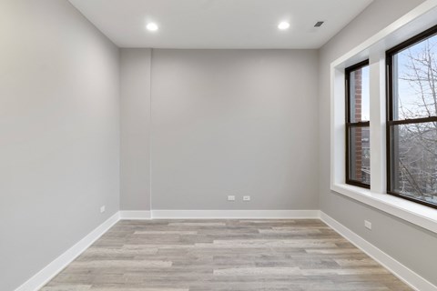 a room with white walls and a wood floor and two windows