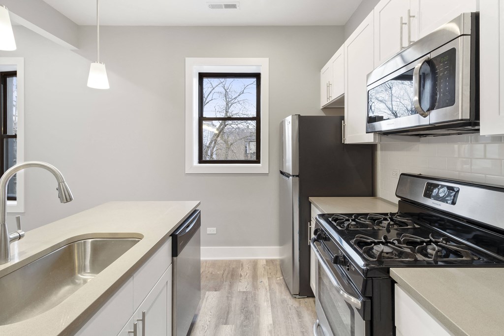 an empty kitchen with stainless steel appliances and a window