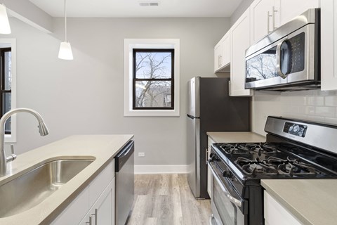 an empty kitchen with stainless steel appliances and a window