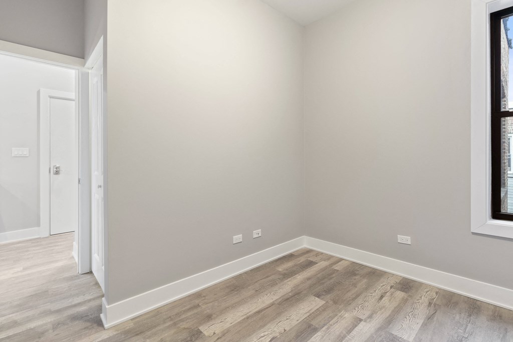 an empty room with wood flooring and a window