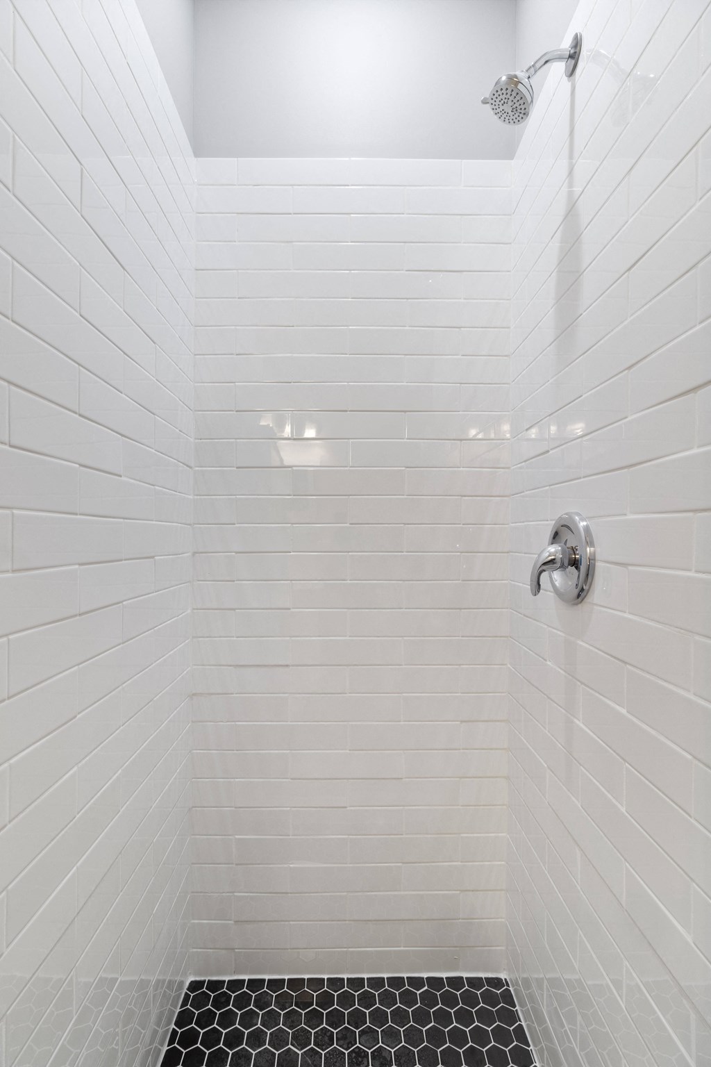 a white tiled shower with white subway tiles and a shower head