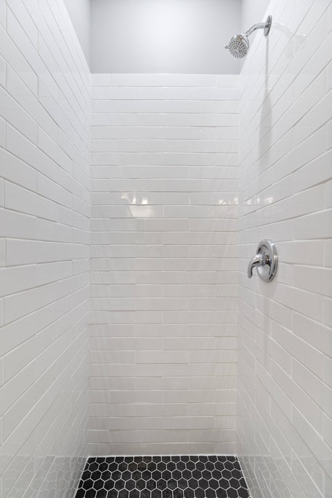 a white tiled shower with white subway tiles and a shower head
