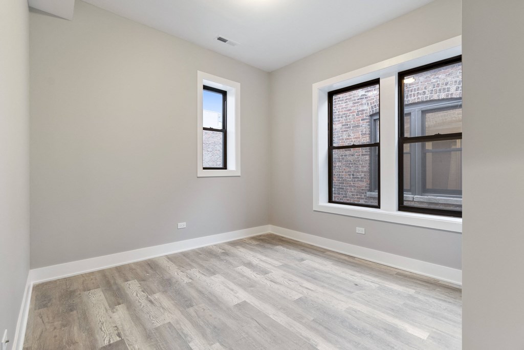 an empty room with two windows and wood floors