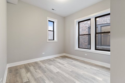 an empty room with two windows and wood floors
