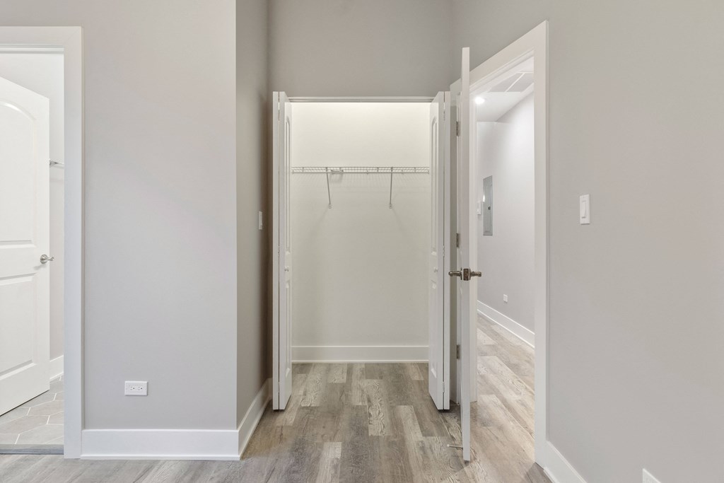 an empty bedroom with a closet and a door to a shower