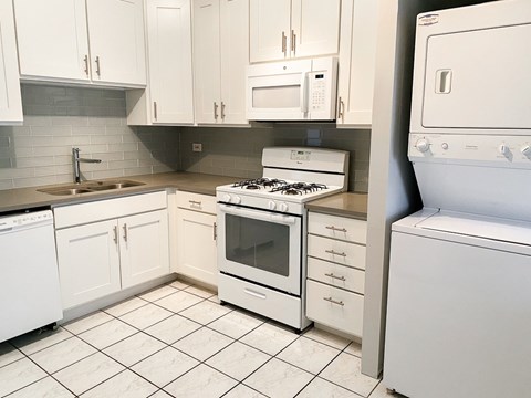 A white kitchen with a stove top oven and a microwave.
