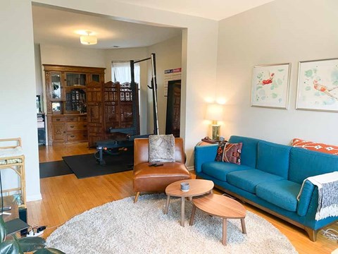 A living room with a blue couch, a brown chair, and a white rug.