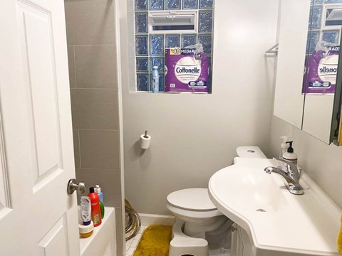 A bathroom with a toilet, sink, and a yellow rug.