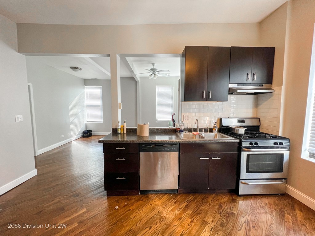 an empty kitchen with wooden floors and stainless steel appliances