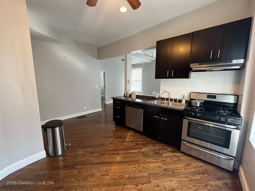 an empty kitchen with black cabinets and stainless steel appliances