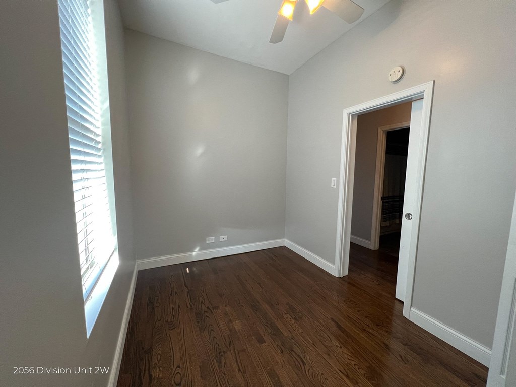 a bedroom with wood flooring and a window