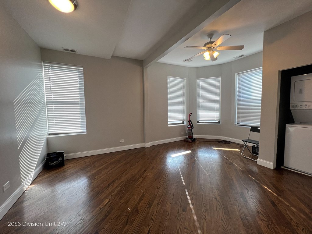 an empty living room with wood floors and a ceiling fan