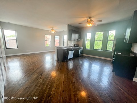 A spacious living room with wood flooring and a ceiling fan.