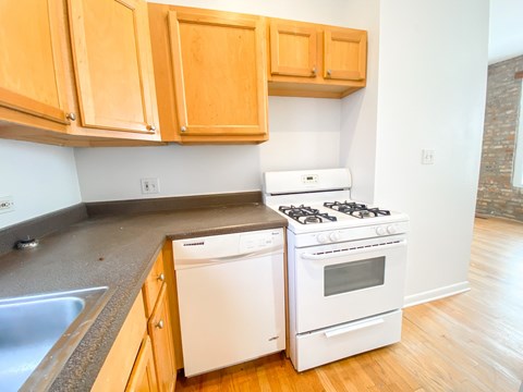 A white dishwasher and stove in a kitchen with wooden cabinets.