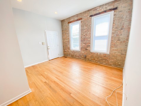A room with wooden floors and a brick wall.
