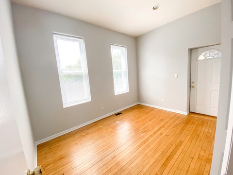 A room with wooden floors and two windows.