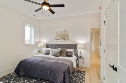 A bedroom with a bed, pillows, a ceiling fan, and a wall art piece.