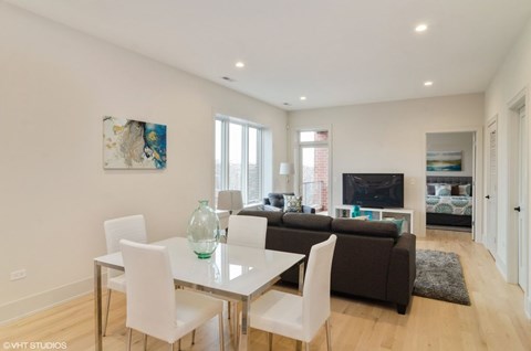 A modern living room with a glass dining table and white chairs.