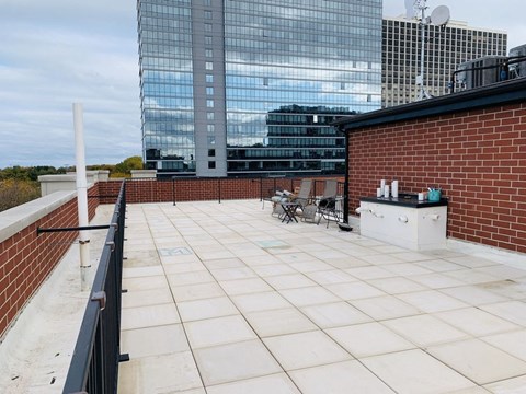 A rooftop patio with a table and chairs overlooking a cityscape.