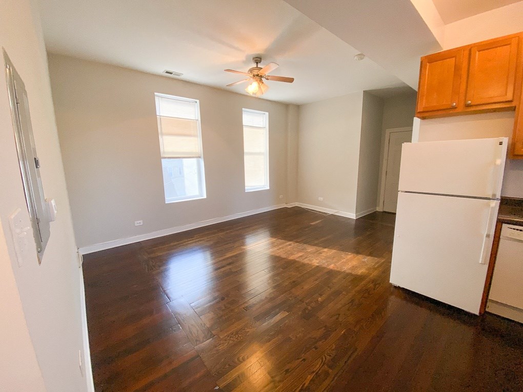 an empty kitchen and living room with wood floors and a ceiling fan