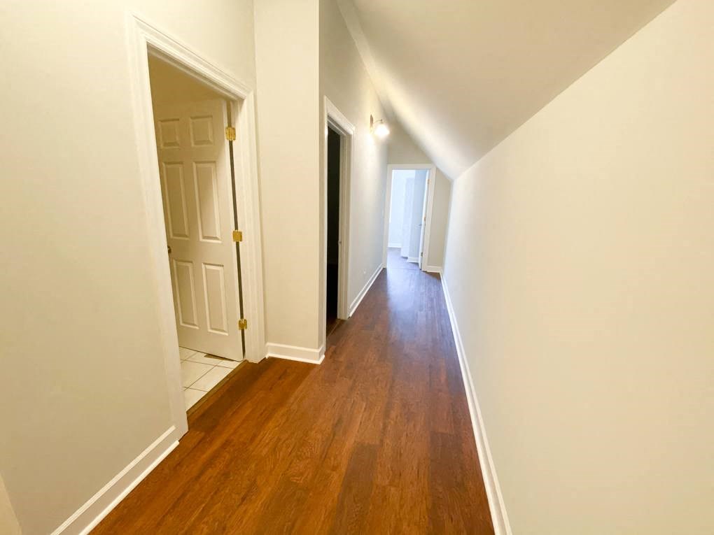 a renovated hallway with a wood floor and white walls