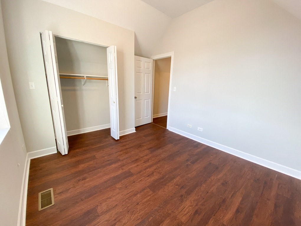 an empty living room with wood flooring and a closet