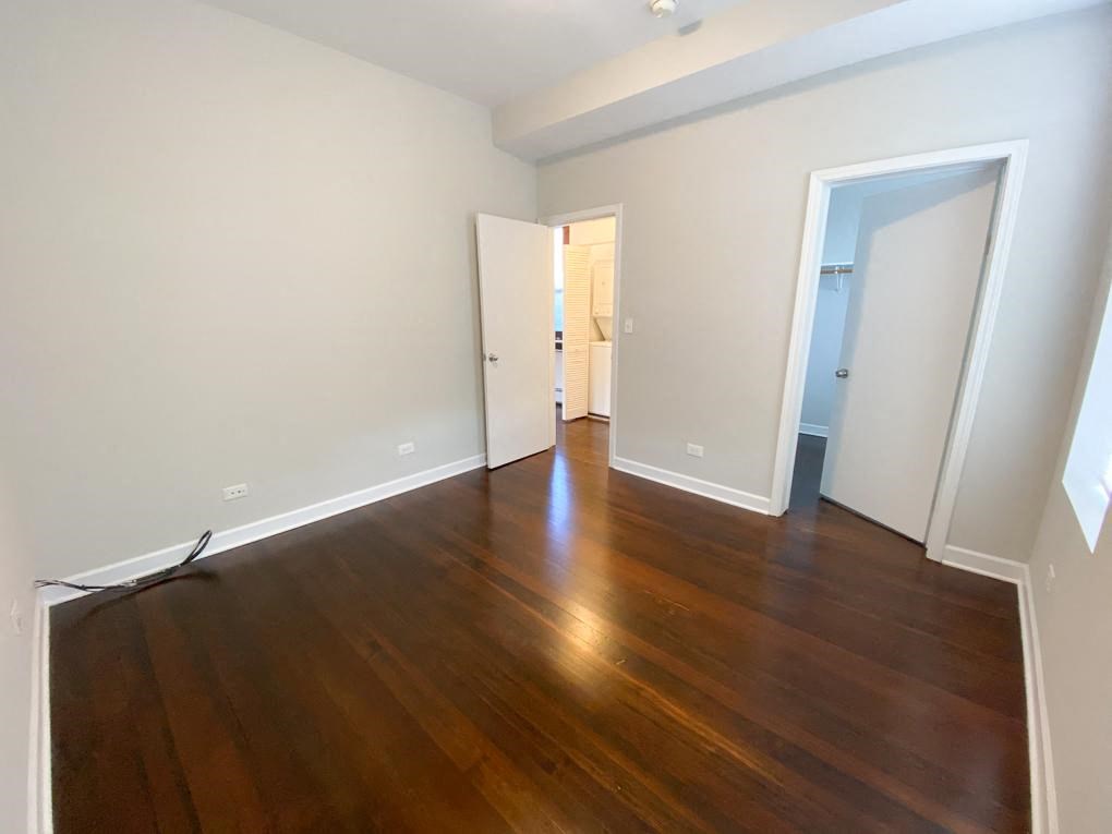 a living room with wood floors and a door to a bedroom