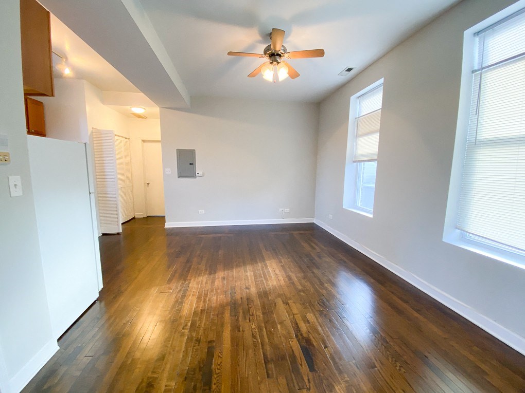 an empty living room with wood floors and a ceiling fan