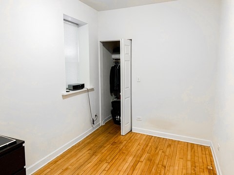 A room with a wooden floor and a white wall with a doorway leading to another room.