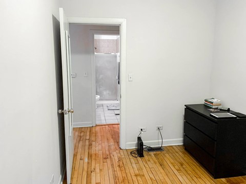 A room with a black dresser and a wooden floor.