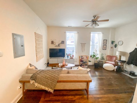 A living room with a couch and a fan.