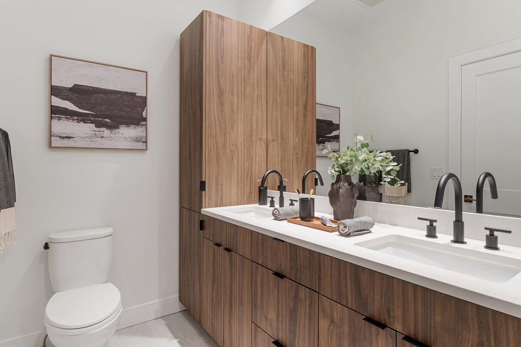 A bathroom with a toilet, sink, and a cabinet.