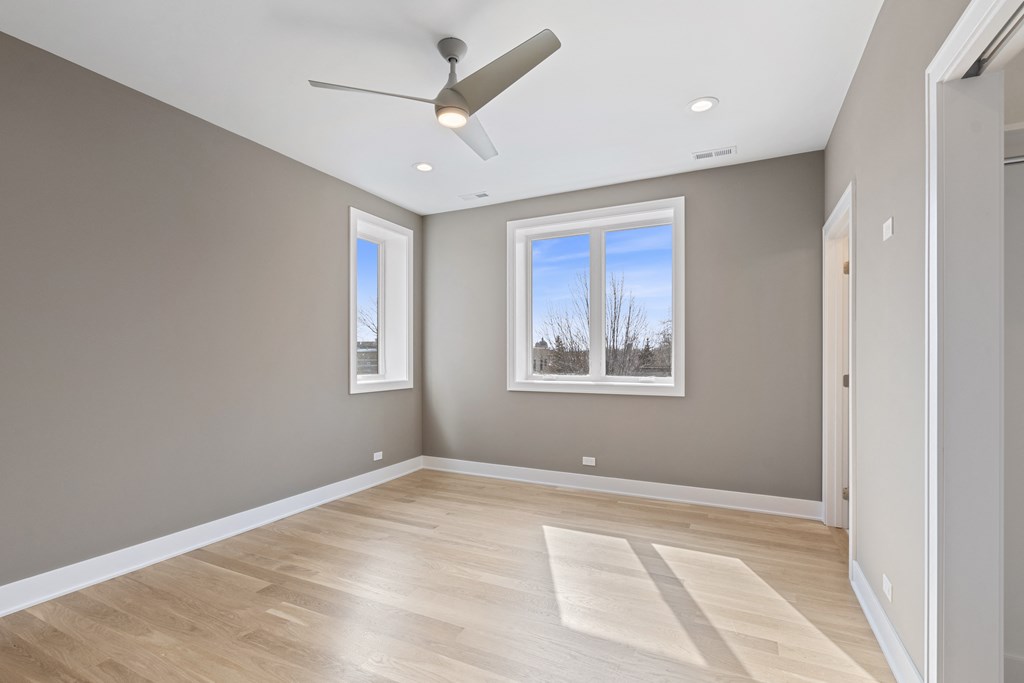 an empty room with a ceiling fan and two windows
