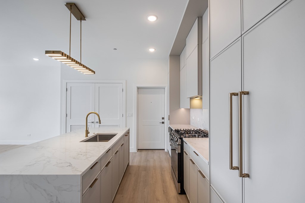 A modern kitchen with a marble countertop and wooden floors.