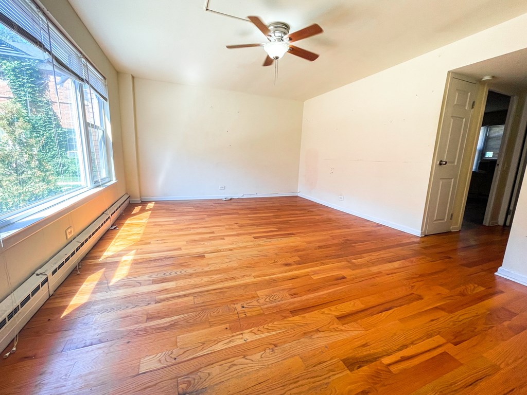 A room with wooden flooring and a ceiling fan.