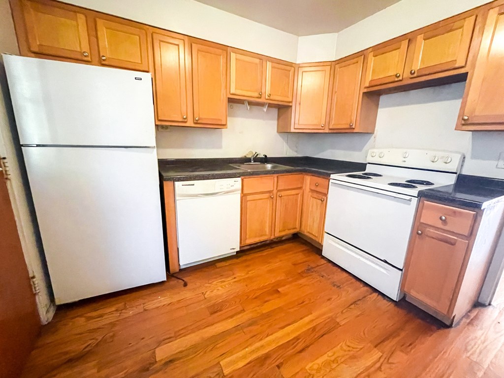 A kitchen with wooden cabinets and a white fridge.