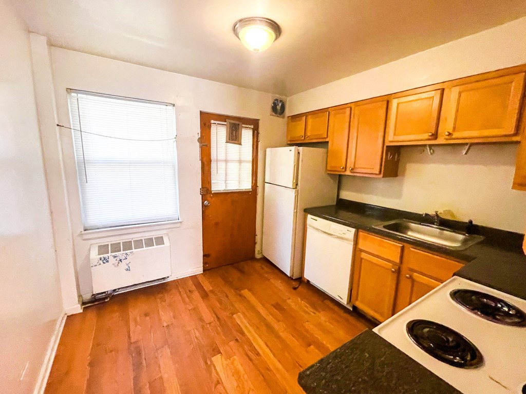 A kitchen with wooden floors and white appliances.