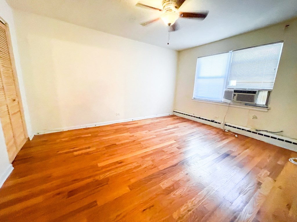 A room with a ceiling fan and wooden flooring.