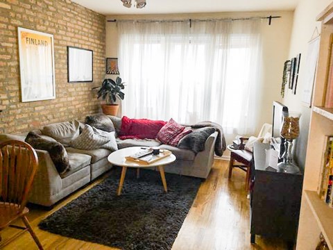 A living room with a grey couch and a red throw on it.