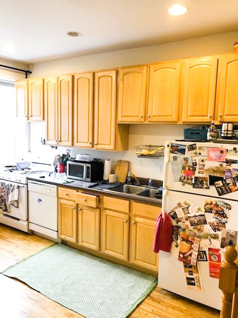 A kitchen with wooden cabinets and a white fridge covered in magnets.