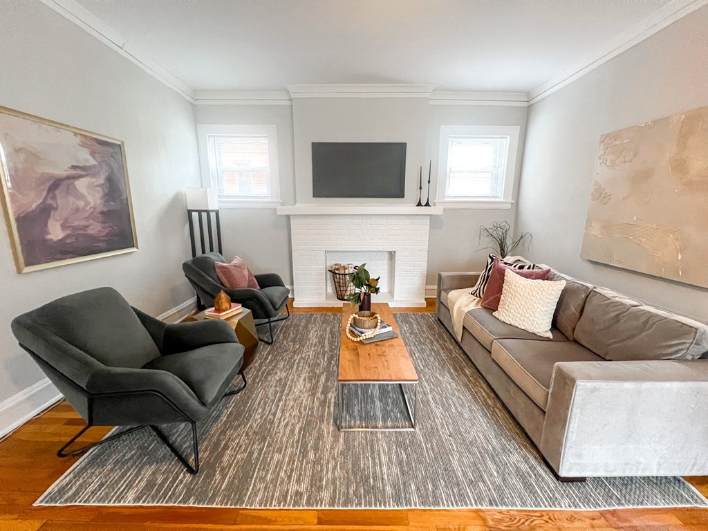 A living room with a grey couch, a black chair, and a fireplace.