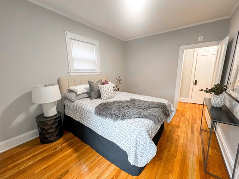A bedroom with a bed, a lamp, and a table.