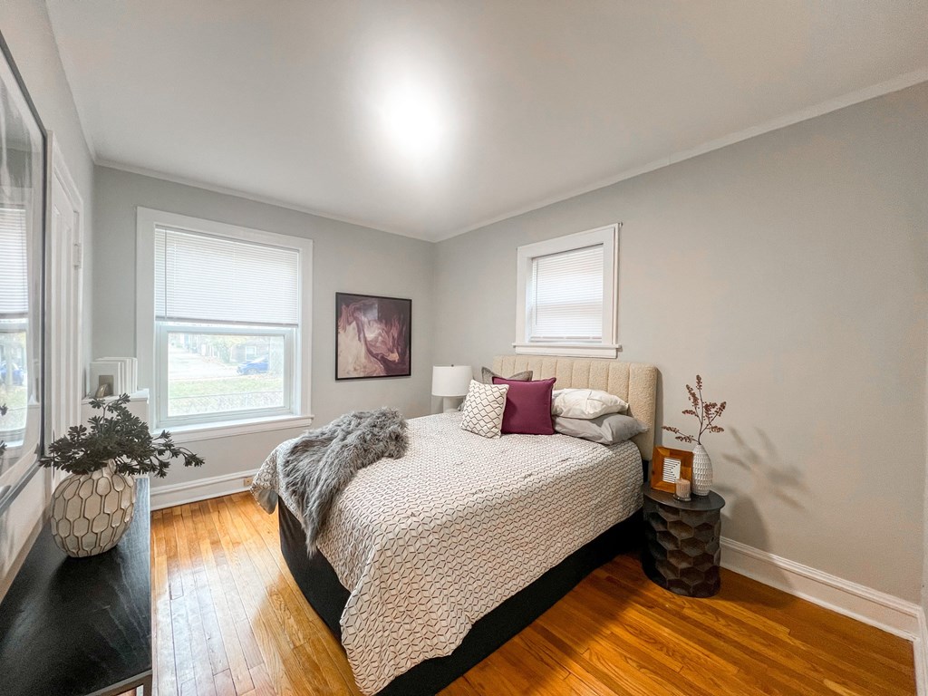 A bedroom with a large bed and a wooden floor.