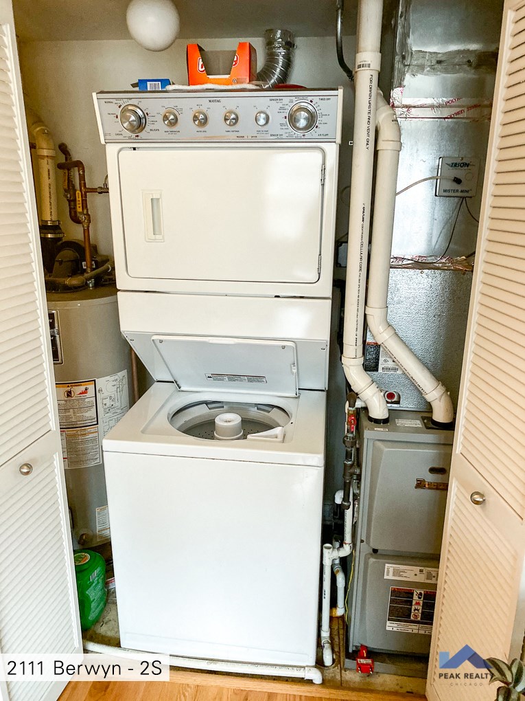 a washer and dryer in a small room with a boiler and pipes