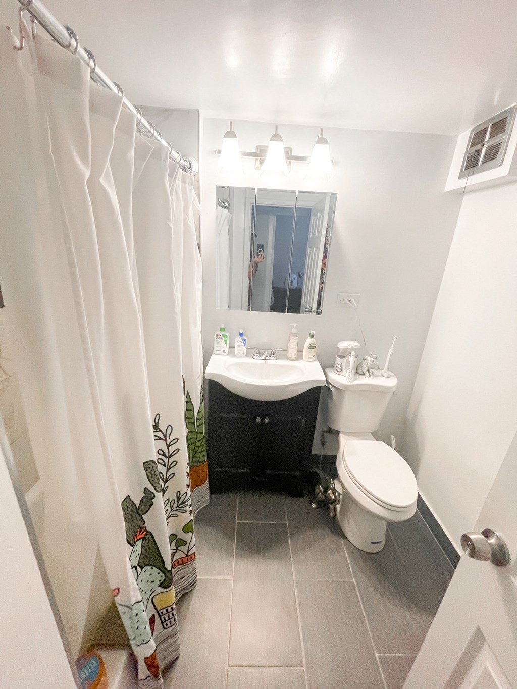 a small bathroom with a white sink and toilet and a white shower curtain with a plant on