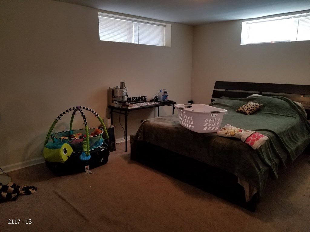a bedroom with a bed and a toy basket on the floor