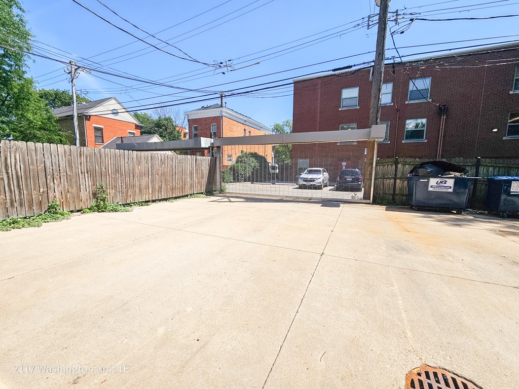 a driveway with a fence and brick buildings on either side of it